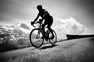 Cyclist on mountain pass, Eiger in the background, descent from Bussalp, Bernese Oberland, Switzerland