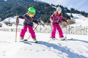 Mädchen und Junge während dem Skifahren auf der Piste, Pfronten, Allgäu, Bayern, Deutschland