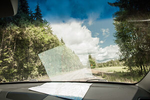 Blick durch die Frontscheibe des Autos mit der Landkarte auf dem Armaturenbrett, Landstrasse, Halland, Schweden