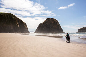 Distant Caucasian woman riding bicycle on beach
