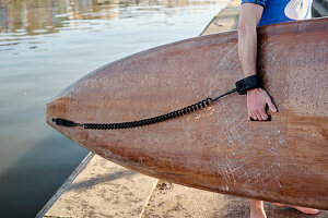 Mann hält Paddleboard neben einem Fluss (Close up)