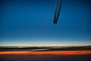 Airplane with contrails just before sunrise