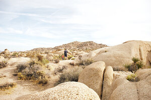 Vater und Sohn wandern in der Felsenlandschaft der Jumbo Rocks im Joshua Tree Park, Kalifornien, USA