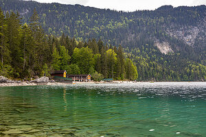 Blick über das türkise Wasser des Eibsee auf Wälder und Hütten am See, Grainau, Oberbayern, Deutschland