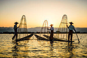 Drei Fischer fischen auf dem Inles-See mit traditionellen kegelförmigen Fischernetzen.