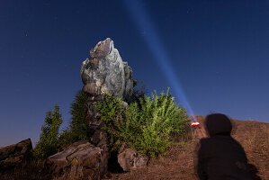 Mann leuchtet mit Taschenlampe einen Felsen der Teufelsmauer an, links oben im Bild eine Sternschnuppe der Perseiden, Weddersleben, Thale, Harz, Sachsen-Anhalt, Deutschland