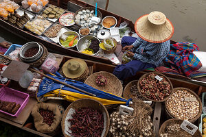 Thailand, Amphawa Floating Market. Woman prepares food for customer in her dugout canoe.