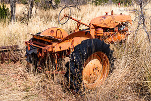 Rusted oldtimer tractor wreck left behind in a field.