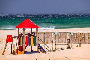 A colorful playground on the stormy sandy beach of Conil de la Frontera on the Andalusian Costa de la Luz, Spain