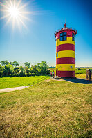 Der Pilsumer Leuchtturm auf dem Nordseedeich im Sommer mit blauem Himmel in der Nähe von Greetsiel, Gemeinde Krummhörn, Niedersachsen, Deutschland