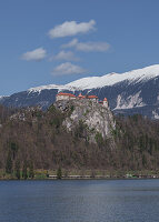 Die Bleder Burg und das dahinter liegende verschneite Gebirge in Bled, Slowenien, Europa.