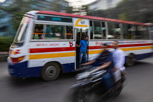 Gezoomtes Bild eines öffentlichen Busses und fahrendes Motorrad, in der Innenstadt von Dhaka, Dhaka, Bangladesch, Asien