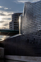  Jogger on bridge in front of Guggenheim Museum, Bilbao. Sun reflecting on facade. Basque Country, Spain 