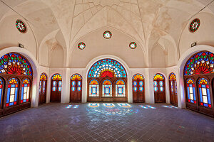  Großer Raum mit bunten Buntglasfenstern im Tabatabaei-Haus, einem historischen Herrenhaus, das um 1880 in Kashan, Iran, erbaut wurde. 