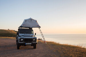 Geländewagen mit Dachzelt campt an der Ostsee bei Sonnenaufgang, Sommer, Provinz Schonen, Schweden