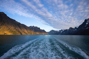 Welle hinter Kiel von Expeditionskreuzfahrtschiff World Voyager (Atlas Ocean Voyages) mit Bergen bei Sonnenuntergang, in der Nähe des Evighedsfjorden (Ewigkeitsfjord), Quetta, Grönland, Europa