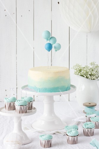 An ombre cake with balloons and chocolate cupcakes