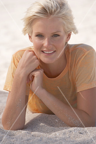 A Mature Blonde Woman With Short Hair On A Beach Wearing A Striped